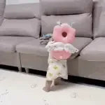 Toddler walking indoors while wearing a pink head protector